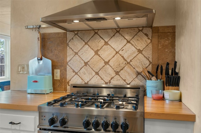 kitchen with stove, backsplash, range hood, and wooden counters