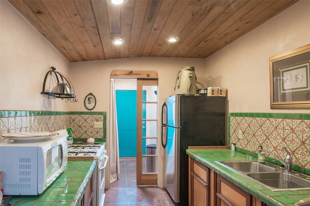 kitchen featuring tile counters, sink, and white appliances