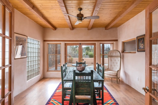 dining room featuring light hardwood / wood-style flooring, wood ceiling, beam ceiling, and french doors