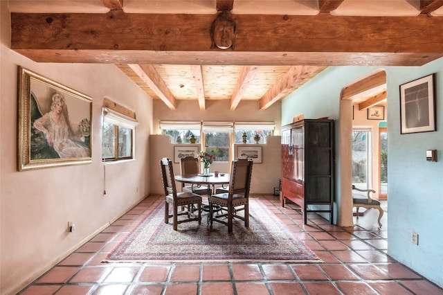 dining room with beam ceiling, tile patterned flooring, and wood ceiling