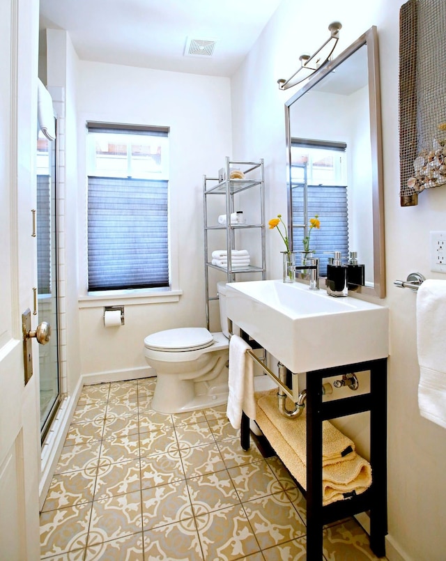 bathroom featuring tile patterned floors, a shower with door, and toilet