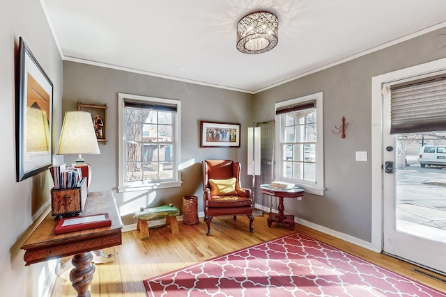 sitting room featuring wood-type flooring and ornamental molding