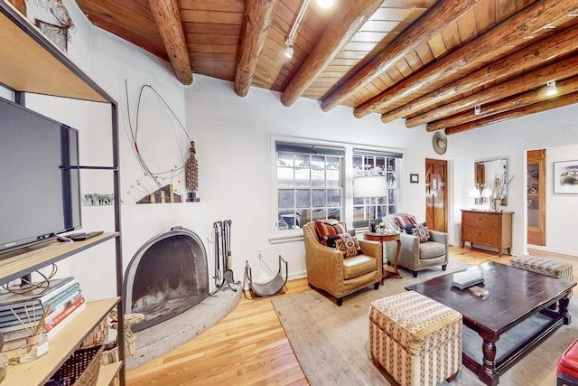 living room with beamed ceiling, wooden ceiling, a fireplace, and light hardwood / wood-style flooring