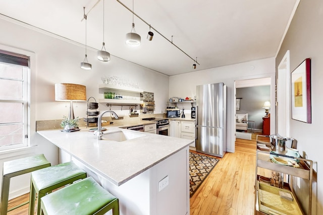 kitchen featuring sink, stainless steel appliances, kitchen peninsula, pendant lighting, and a kitchen bar