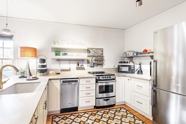 kitchen with sink, white cabinets, decorative light fixtures, and appliances with stainless steel finishes