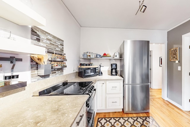 kitchen with appliances with stainless steel finishes, light wood-type flooring, and white cabinetry