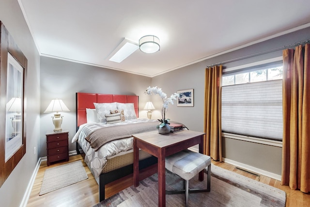 bedroom featuring light wood-type flooring, a skylight, and crown molding