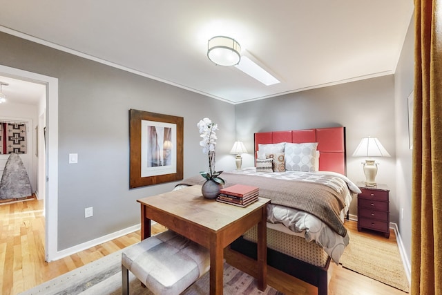 bedroom featuring ornamental molding, light hardwood / wood-style flooring, and a skylight