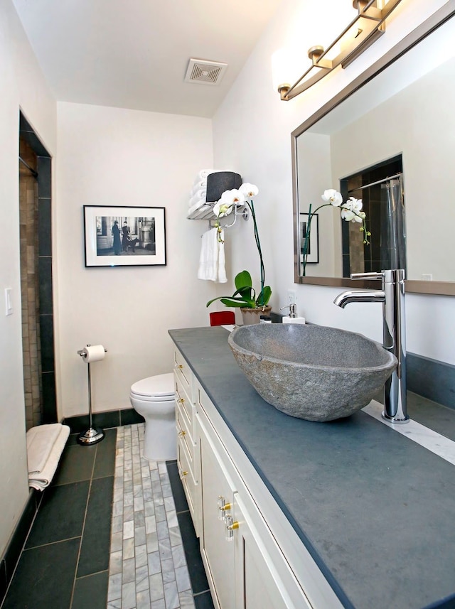 bathroom with tile patterned floors, walk in shower, vanity, and toilet