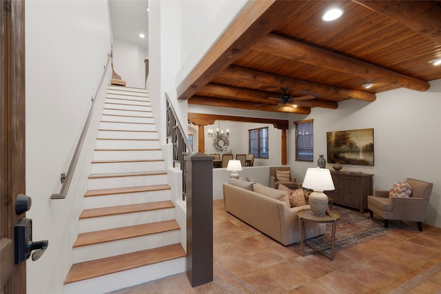 living room featuring beamed ceiling, ceiling fan with notable chandelier, and wooden ceiling