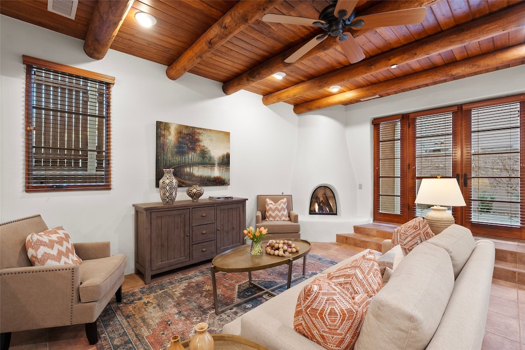 living room featuring ceiling fan, light tile patterned floors, wooden ceiling, and beamed ceiling