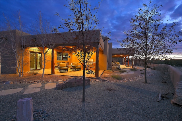 back house at dusk featuring an outdoor hangout area and a patio