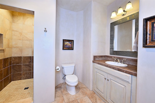 bathroom with tiled shower, vanity, and toilet