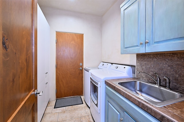 washroom featuring washing machine and clothes dryer, sink, light tile patterned floors, and cabinets