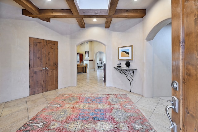 tiled foyer featuring beam ceiling