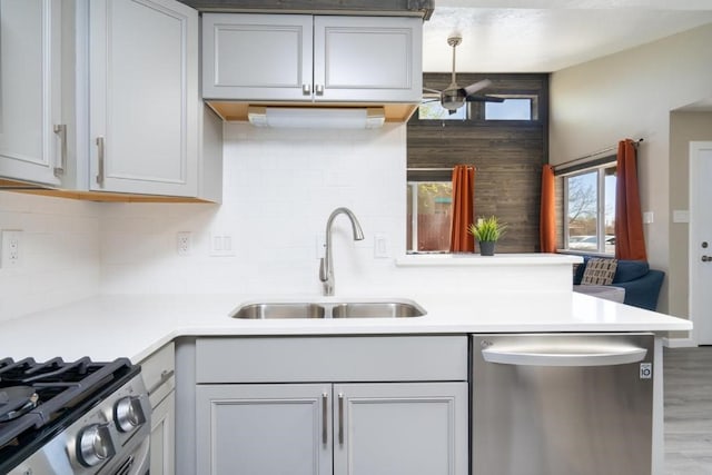 kitchen featuring sink, ceiling fan, decorative backsplash, appliances with stainless steel finishes, and kitchen peninsula