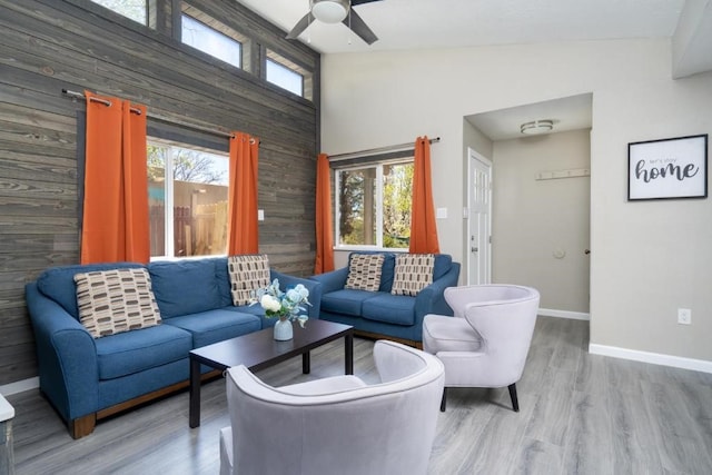 living room featuring ceiling fan, wood walls, and light hardwood / wood-style flooring