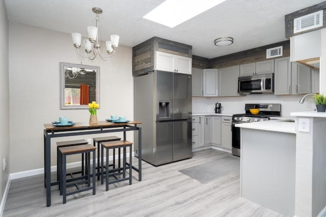 kitchen featuring sink, decorative light fixtures, light hardwood / wood-style flooring, a notable chandelier, and stainless steel appliances