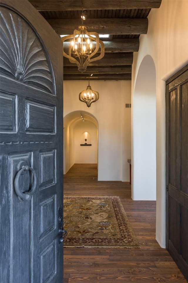 hall featuring beam ceiling, dark hardwood / wood-style floors, and an inviting chandelier