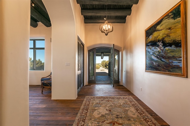 entryway with beamed ceiling, a towering ceiling, dark hardwood / wood-style flooring, and a chandelier