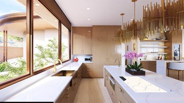 kitchen featuring white electric stovetop, sink, hanging light fixtures, and light stone counters