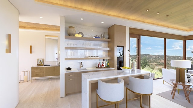 kitchen featuring sink, light stone counters, a kitchen bar, wood ceiling, and light wood-type flooring