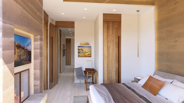 bedroom featuring light wood-type flooring and wood walls