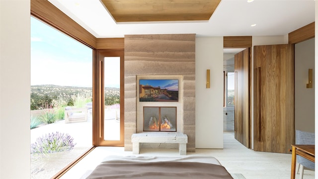 unfurnished living room with a large fireplace, a tray ceiling, and light hardwood / wood-style floors