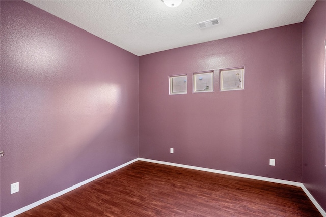 unfurnished room with hardwood / wood-style flooring and a textured ceiling