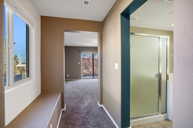 hall with light carpet and a textured ceiling