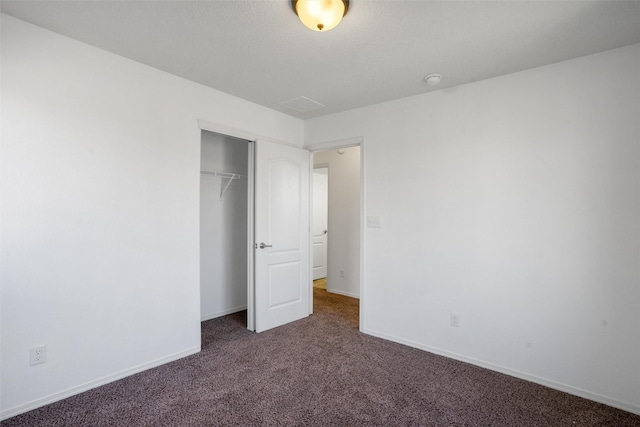 unfurnished bedroom with a closet and dark colored carpet