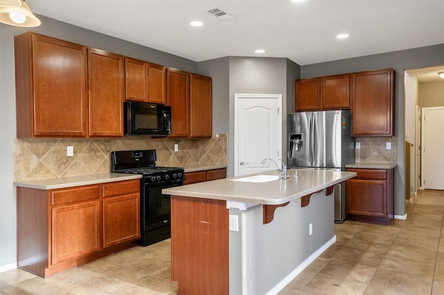 kitchen with sink, a kitchen breakfast bar, backsplash, an island with sink, and black appliances