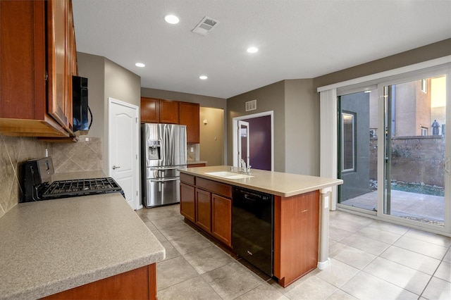 kitchen featuring backsplash, black appliances, sink, light tile patterned floors, and an island with sink