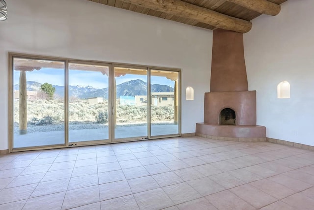 unfurnished living room with a mountain view, wooden ceiling, light tile patterned flooring, a fireplace, and beam ceiling