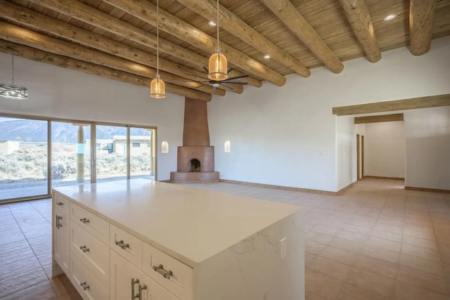 kitchen featuring ceiling fan, beamed ceiling, white cabinetry, hanging light fixtures, and wooden ceiling