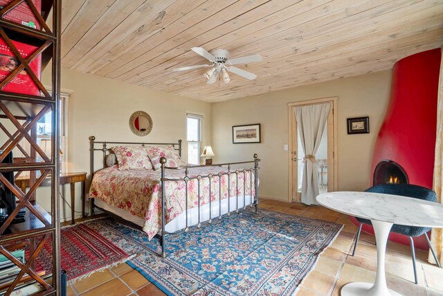 bedroom with ceiling fan, wood ceiling, tile patterned flooring, and a large fireplace