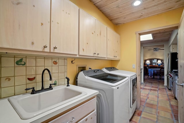 clothes washing area featuring separate washer and dryer, cabinets, and sink