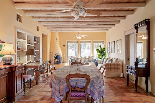 tiled dining room with a large fireplace, beam ceiling, and wood ceiling