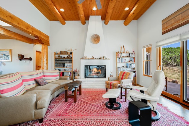 living room with beam ceiling, ceiling fan, a fireplace, and wooden ceiling