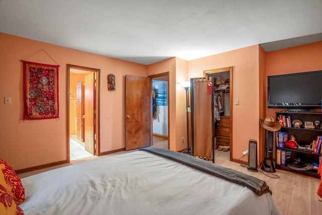 bedroom featuring a walk in closet, ensuite bathroom, a closet, and light hardwood / wood-style floors