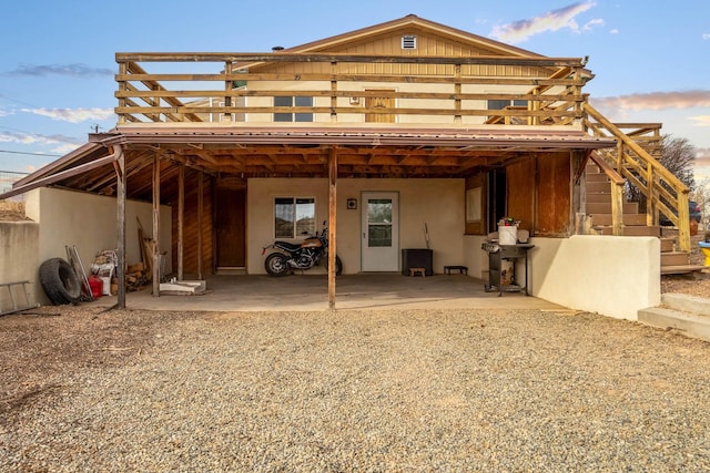 back house at dusk featuring a carport and a wooden deck