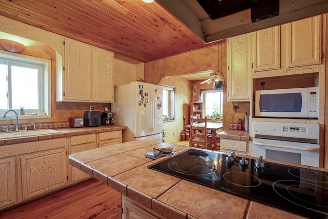 kitchen with white appliances, sink, tile counters, light hardwood / wood-style floors, and wood ceiling