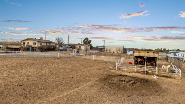 yard at dusk featuring a rural view