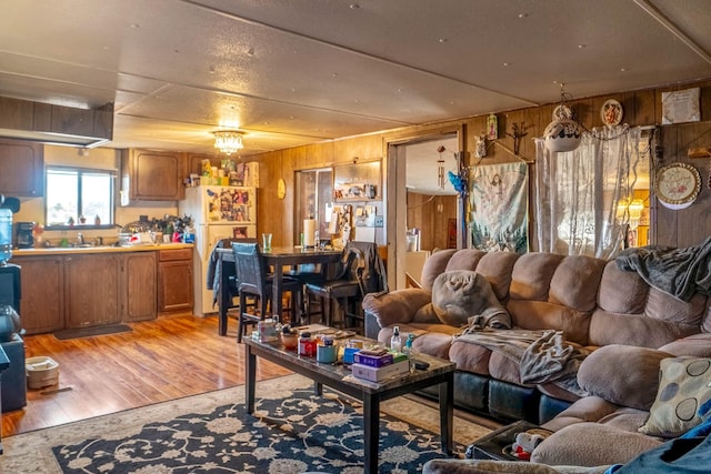 living room with wood walls, light hardwood / wood-style flooring, and sink