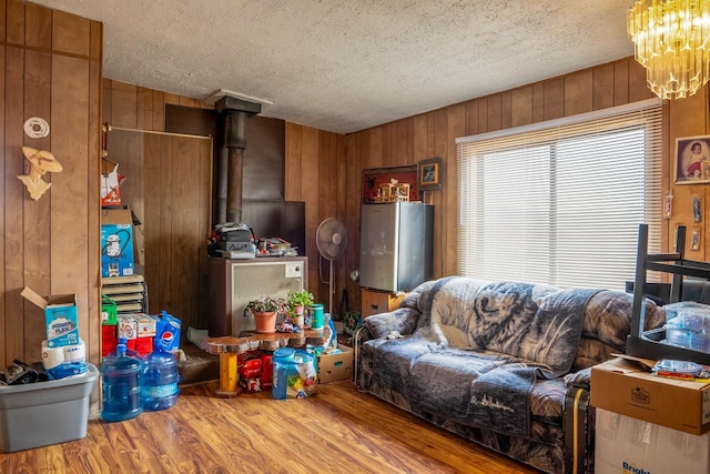 living room with hardwood / wood-style floors, a textured ceiling, a wood stove, and wood walls