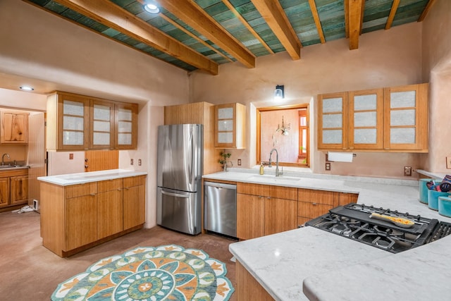 kitchen with beamed ceiling, light stone counters, sink, and appliances with stainless steel finishes