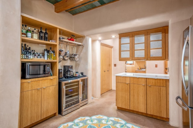 kitchen with appliances with stainless steel finishes, beverage cooler, and beam ceiling