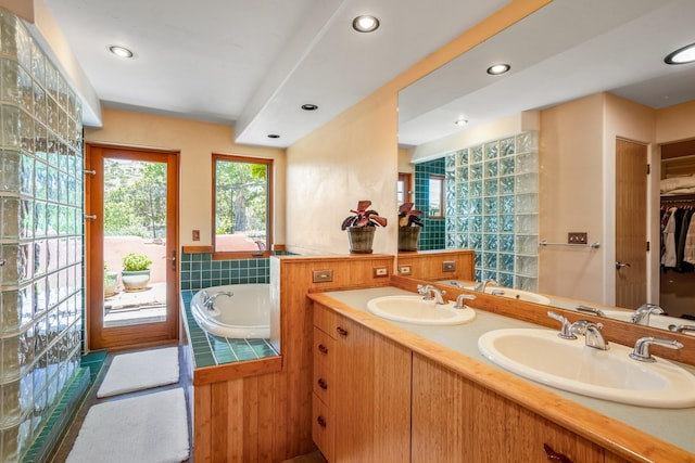 bathroom with tile patterned flooring, vanity, and a relaxing tiled tub