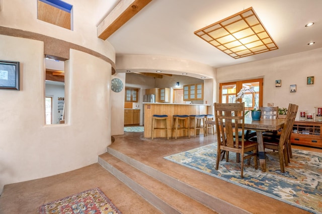 dining space featuring beamed ceiling and concrete flooring