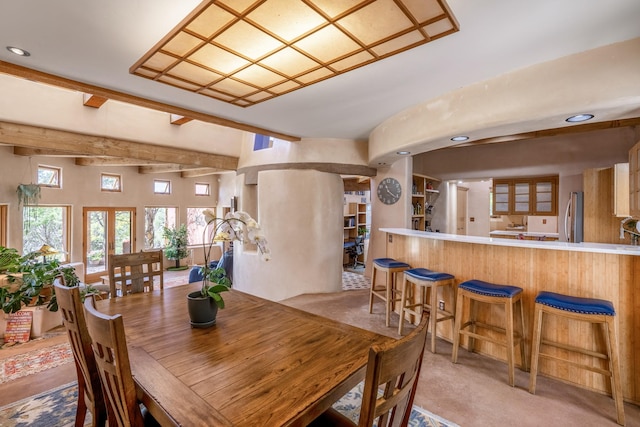 carpeted dining area with beam ceiling